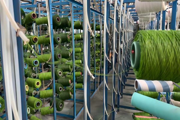 QH Grass factory workers inspecting a roll of artificial turf