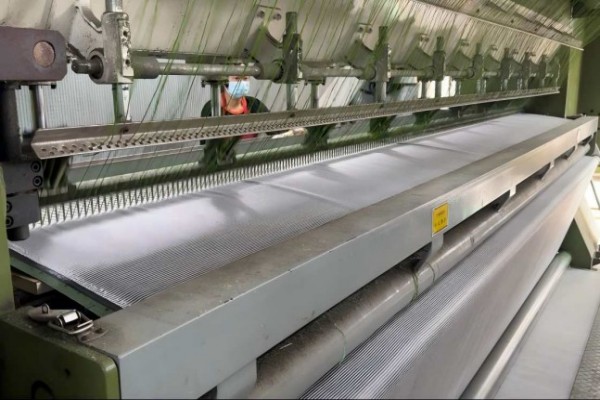 Tufting machine with hundreds of needles stitching yarn into a backing fabric