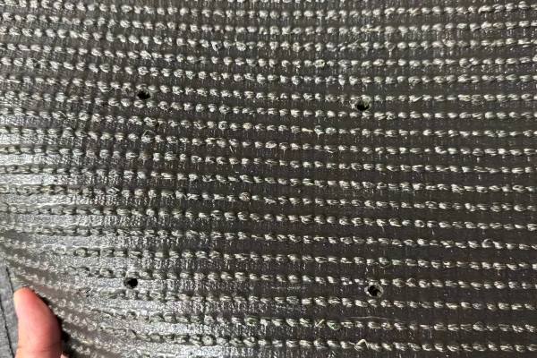 A close-up shot of pet turf showing drainage holes