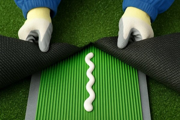 Two pieces of artificial grass being joined together over seam tape