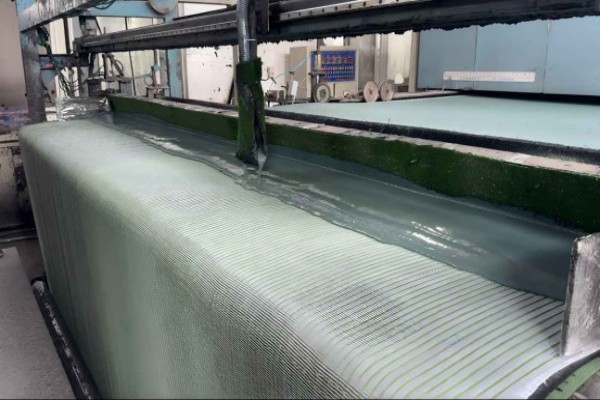 A machine applying a black latex coating to the back of artificial grass