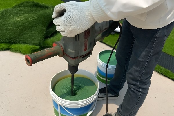Mixing the two components of a turf adhesive in a bucket