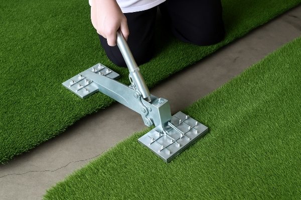 Two Turf Fix tools holding turf fibers back on either side of a seam