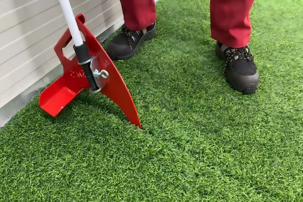 A Seam Fix roller being used to press down on a freshly glued artificial turf seam