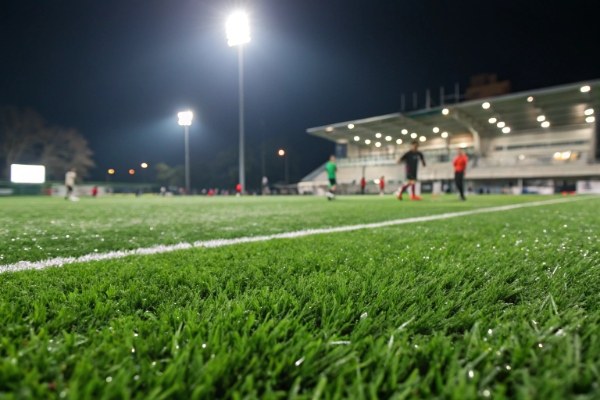Lush green artificial turf soccer field under bright stadium lights