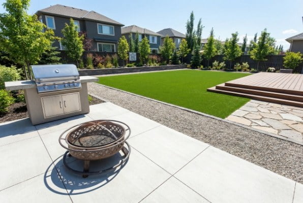 barbecue grill on stone patio near artificial grass